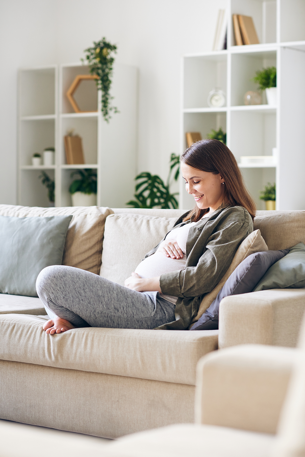 pregnant woman holding stomach at window
