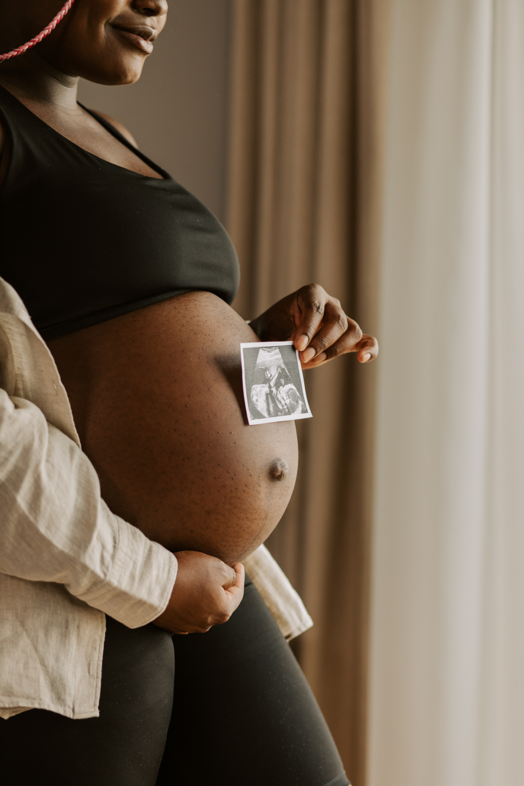 pregnant woman holding stomach at window